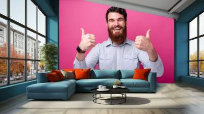 Cheerful bearded man in casual showing thumbs up gesture Wall mural