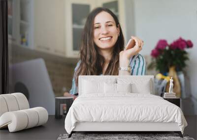 cheerful smiling young woman looking at camera, work from home Wall mural