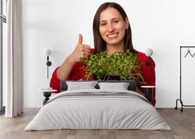 Cheerful young woman is holding some micro greens and showing thumb up. The are healthy for you. Wall mural