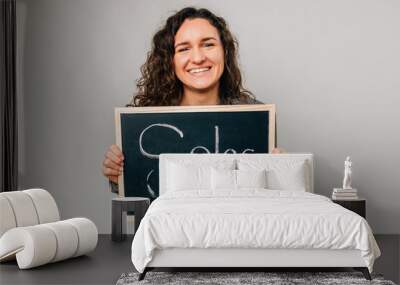 Ecstatic curly young woman is holding a black board with word sales on it. Wall mural