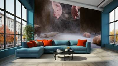 hand of chef clap a flour with wooden rolling pin and ingredients on dark background Wall mural