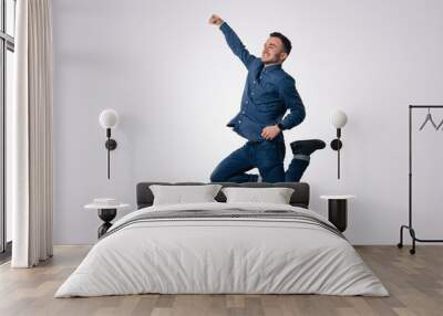 Happy excited cheerful young man jumping and celebrating success over white background Wall mural