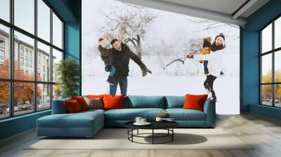 Happy family day. beautiful young family  is throwing with snow in park Wall mural