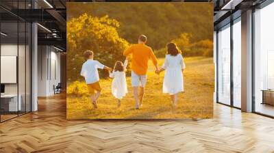 Photo from back, handsome family walking together in a field, on sunset Wall mural