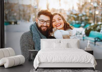 Photo of a cute  couple hugging, winter walking in park, looking and smiling at camera Wall mural