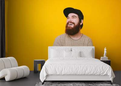 Portrait of cheerful bearded man smiling and looking away over yellow background Wall mural