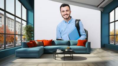 Portrait of cheerful handsome man holding laptop and phone over white background and looking at the camera. Wall mural