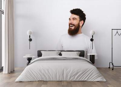 Portrait of cheerful smiling young man with beard in white t-shirt looking away at copyspace Wall mural