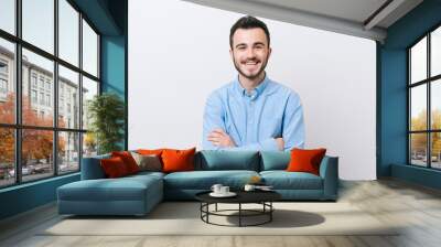 Portrait of cheerful young man in casual with crossed arms smiling over white background and looking at the camera Wall mural