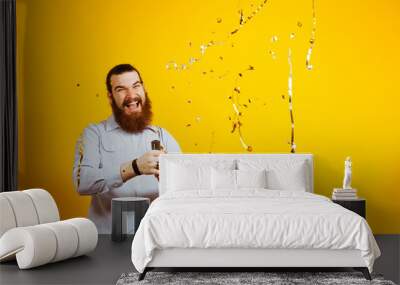 Portrait of Screaming bearded hipster man throwing confetti over yellow background, copyspace, free space for text. Businessman throwing confetti in the air. Wall mural