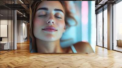 A tranquil and serene close-up of a woman with closed eyes and a content smile, representing relaxation and inner peace, set against a soothing and calm ambiance. Wall mural