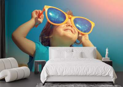 Happy little girl with big sunglasses looking at the sun Wall mural