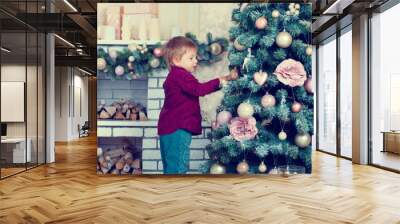 Little boy decorates Christmas fir tree Wall mural