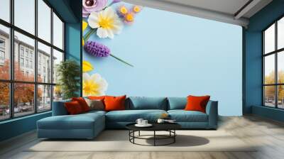 A flat lay of yellow and purple flowers on a pastel blue background creates a charming spring and Easter themed composition with a top down view and plenty of copy space for customization Wall mural