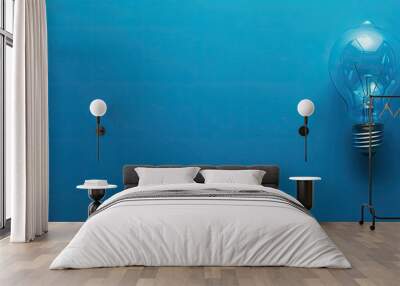 Blue paper background with a single light bulb, copy space image. Wall mural