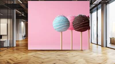 Cake pops on a pink backdrop Mini cakes on a stick Sponge cake coated in chocolate Chocolate cake adorned with colorful icing on a pink background Celebration treats. with copy space image Wall mural