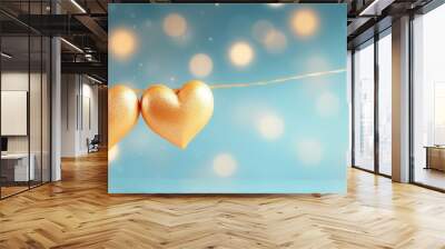 Closeup Valentine s day concept with selective focus featuring two golden hearts a luminous garland and a light blue background Ample copy space for a Valentines day card Wall mural