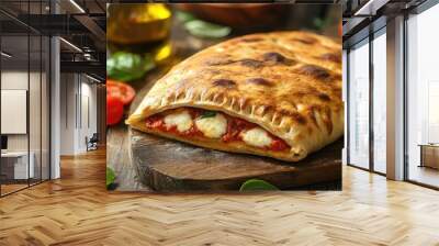 Italian cuisine stuffed calzone pizza on a rustic wooden surface In the background are small red tomatoes mozzarella basil and olive oil. with copy space image. Place for adding text or design Wall mural