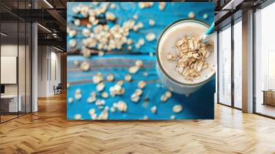 Oat milk in a glass with a blue paper straw on a wooden surface with copy space Wall mural