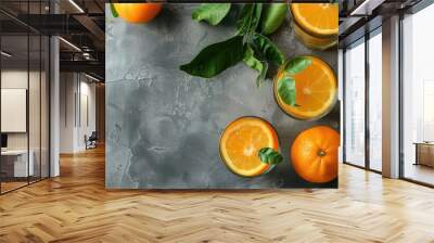 Top view of tangerines with leaves in glasses of citrus fruit juice on a table with a grey background including copy space image Wall mural