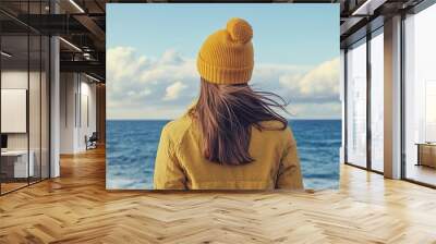 Travel background featuring a young woman standing alone by the sea and sky The image relates to nature portrait individual scenery tourism and lifestyle concepts. with copy space image Wall mural