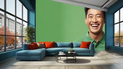 Unappealing smile of an Asian man on green background Wall mural