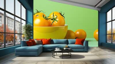 Yellow tomatoes in a white bowl on a green background with copy space image. Wall mural