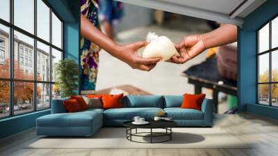 two women's hands holding a ball of cassava couscous Wall mural