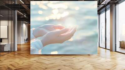 A person's hands are open and facing the camera, with the water in the background. Concept of peace and serenity, as if the person is offering a gesture of love or hope Wall mural