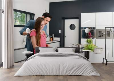 beautiful and happy young couple preparing organic vegetable salad together in kitchen at home Wall mural