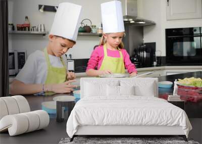 beautiful young happy kids boy and girl cooking and baking a cake in kitchen at home Wall mural