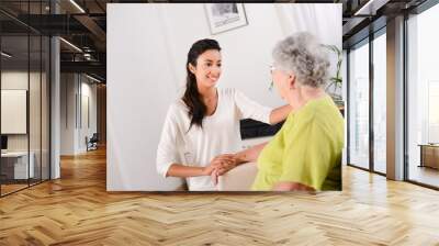 cheerful young girl taking care of elderly woman at home Wall mural