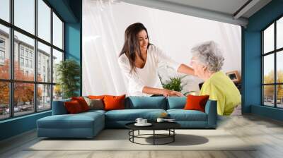 cheerful young girl taking care of elderly woman at home Wall mural