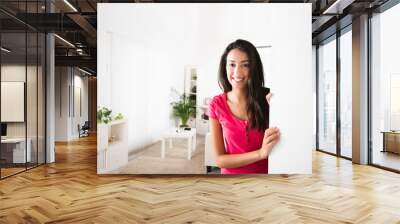 cheerful young woman opening frontdoor inviting friends home Wall mural