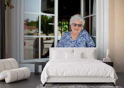 elderly senior woman opening a window of her house and welcoming people at home Wall mural