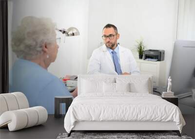 handsome doctor giving medical consultation diagnostic  to elderly senior woman in hospital office Wall mural