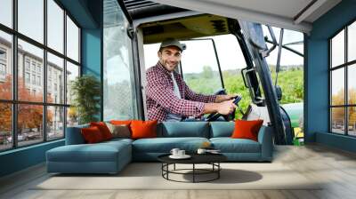 handsome young male farmer driving his tractor during harvest in the field countryside Wall mural