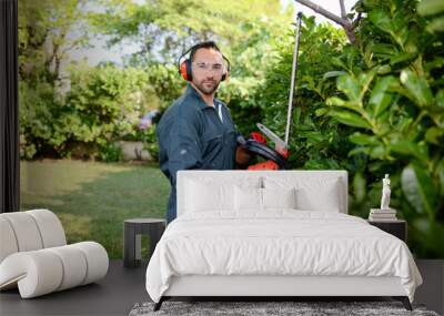 handsome young man gardener trimming hedgerow in a garden park outdoor Wall mural