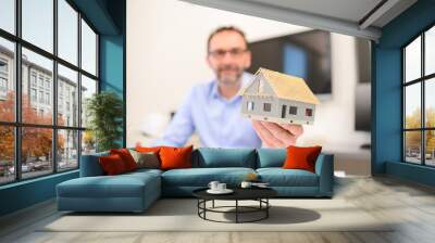 mature male architect showing a mockup sketch of architectural construction house building in architect studio workspace holding meter and keys Wall mural