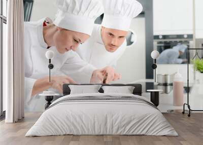 portrait of a cheerful young woman professional pastry cook at work in kitchen decorating a chocolat Wall mural