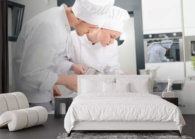 student and teacher in a professional cook school kitchen preparing a plate for restaurant Wall mural