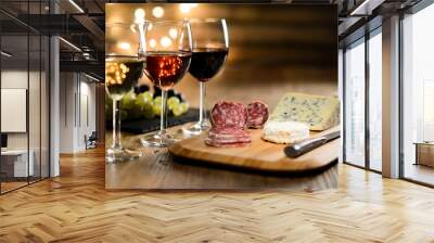 three glass of red wine, rose wine and white wine with french cheese and delicatessen in restaurant wooden table with romantic dim light and cosy atmosphere Wall mural