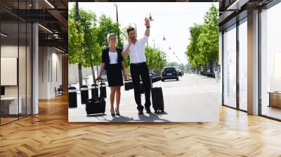 young business couple waving a taxi cab in public station Wall mural