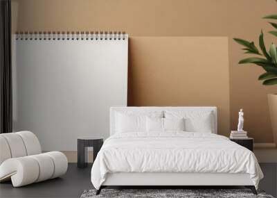 Minimalist workspace featuring a notepad, blank card, and a potted plant against a warm, neutral background. Wall mural