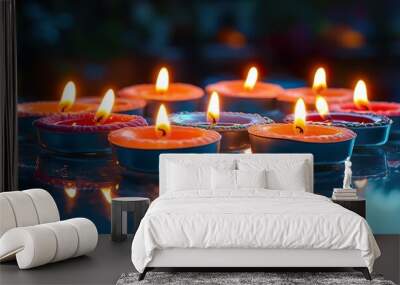 Colorful, decorative Diwali candles arranged in a circular pattern, with glowing reflections on a glass table. Wall mural