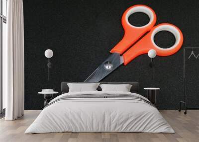 Orange scissors on black background in studio light Wall mural