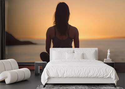 seen from behind Beautiful young woman doing yoga exercises on the beach at sunset Wall mural