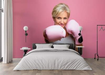 Middle age woman with Pink boxing glove fighting punch to breast cancer Wall mural