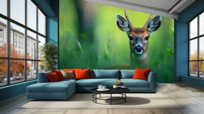  A deer, its antlers crowned against the sky, stands in a field of tall, waving grass Wall mural