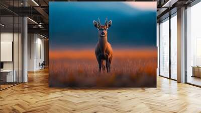  A deer stands in a field with tall grass Mountains and a hazy sky form the background Wall mural